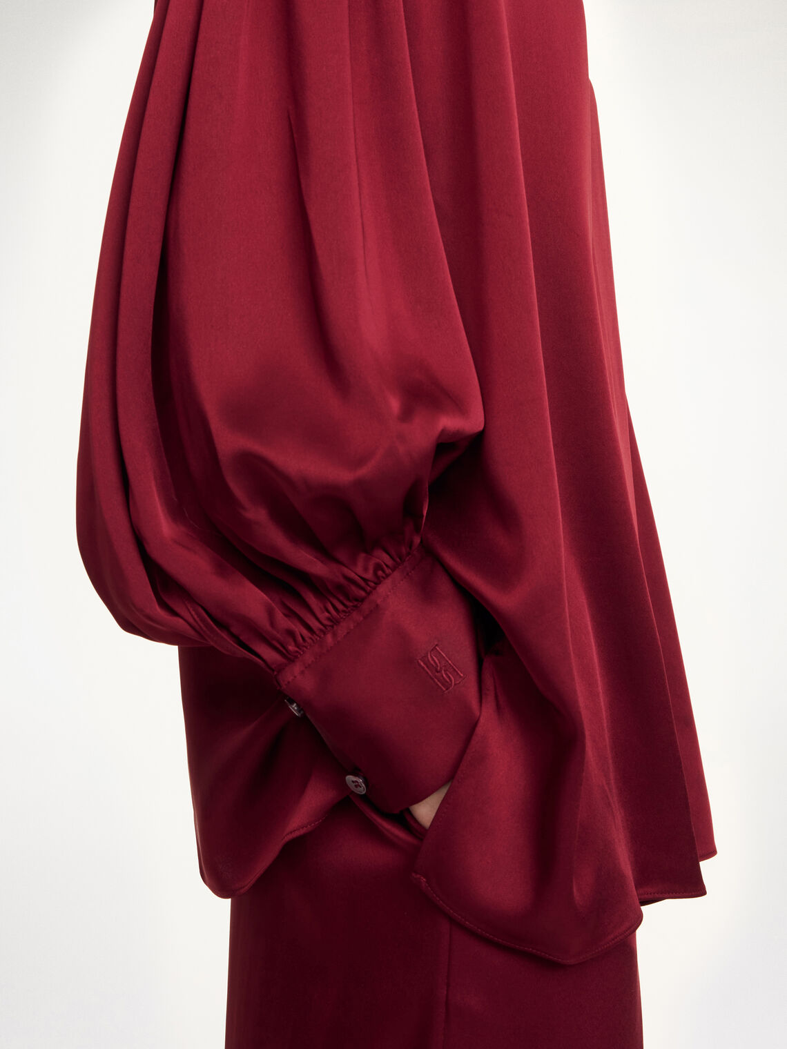 By Malene Birger Leonora satengbluse i burgunder, detalj av v-hals med hempe og sidelomme.