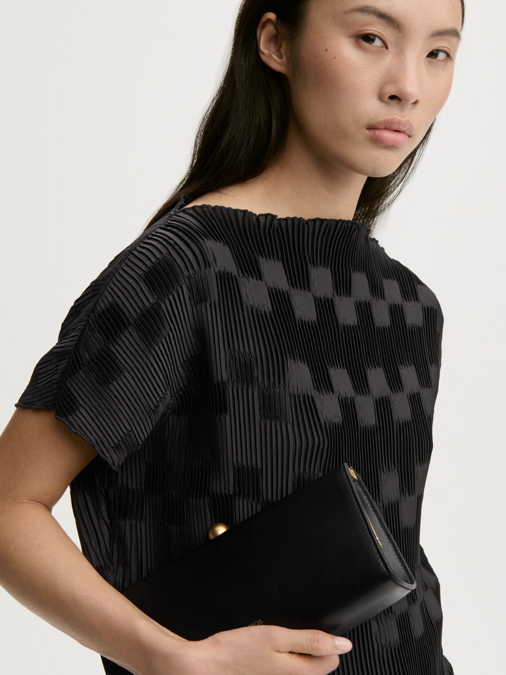 LIANNA plissebluse fra By Malene Birger i fargen sort, laget i 100% resirkulert polyester. Båthals, dropped skuldre og en avslappet, flatterende passform.