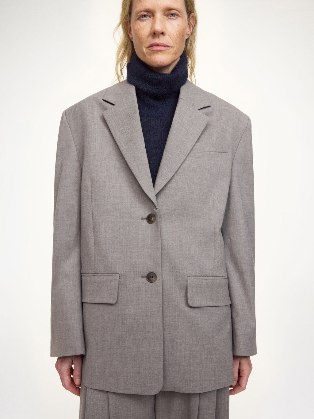 LIVA blazer fra By Malene Birger i grå med brun melering. Laget i ull, polyester og viskose med enkeltspent lukking, lommer i front, innvendig lomme og foret konstruksjon. Noe lang og løs passform.