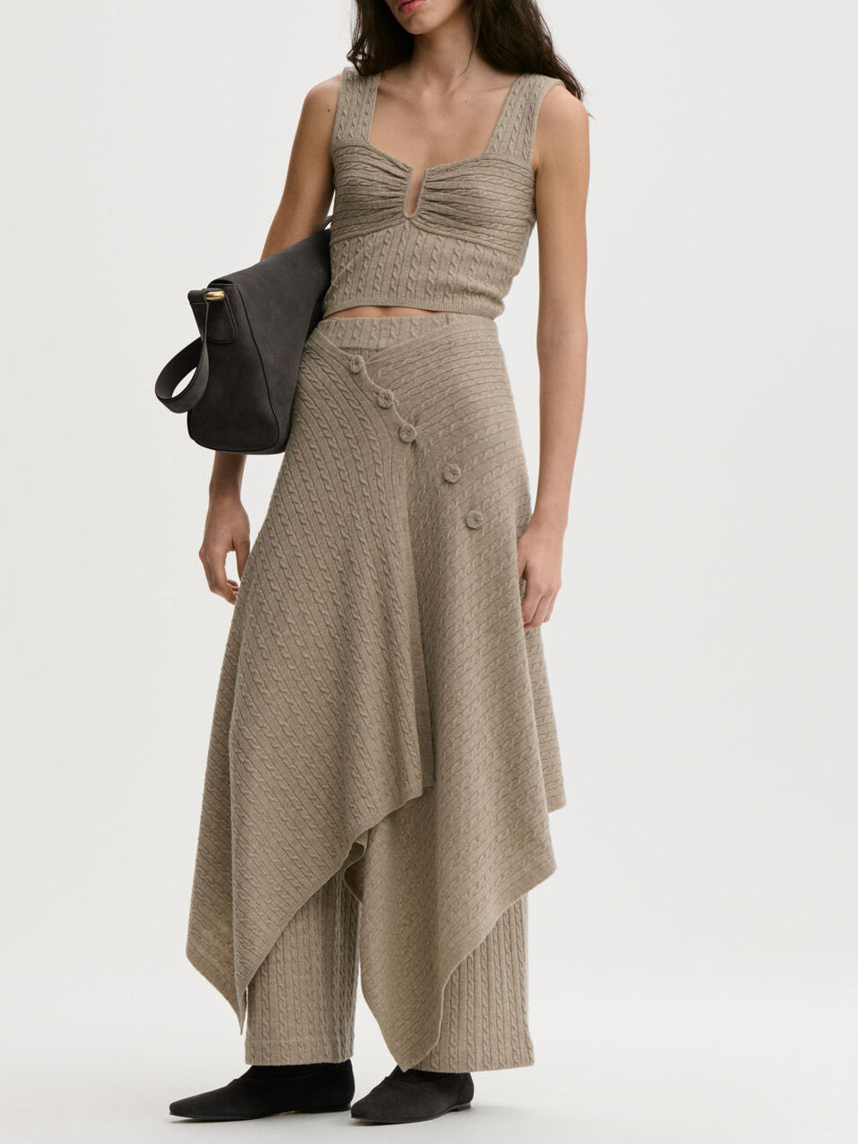 LIZA sjal/cape fra By Malene Birger i fargen beige, laget i 90% ull og 10% cashmere. Kabelstrikket og lukkes med trukne knapper – kan brukes som sjal over skuldrene eller som skjørt rundt livet.