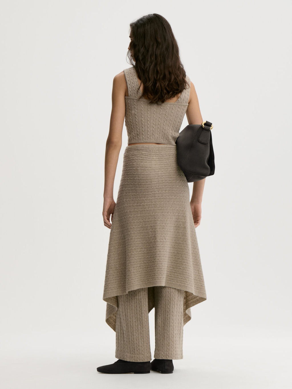LIZA sjal/cape fra By Malene Birger i fargen beige, laget i 90% ull og 10% cashmere. Kabelstrikket og lukkes med trukne knapper – kan brukes som sjal over skuldrene eller som skjørt rundt livet.