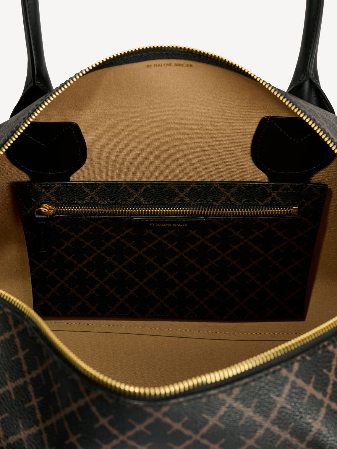 By Malene Birger Lullu small weekendbag i brun, laget av polyvinylklorid med Signature Flower-print og avtagbar skulderreim.