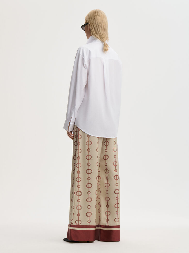 LUNIA bukse fra By Malene Birger med egenutviklet print, laget i 85% acetat og 15% polyester. Høyt liv, strikk i livet, vide ben og lommer i siden.