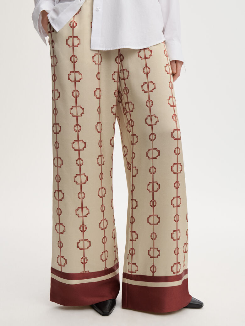 LUNIA bukse fra By Malene Birger med egenutviklet print, laget i 85% acetat og 15% polyester. Høyt liv, strikk i livet, vide ben og lommer i siden.