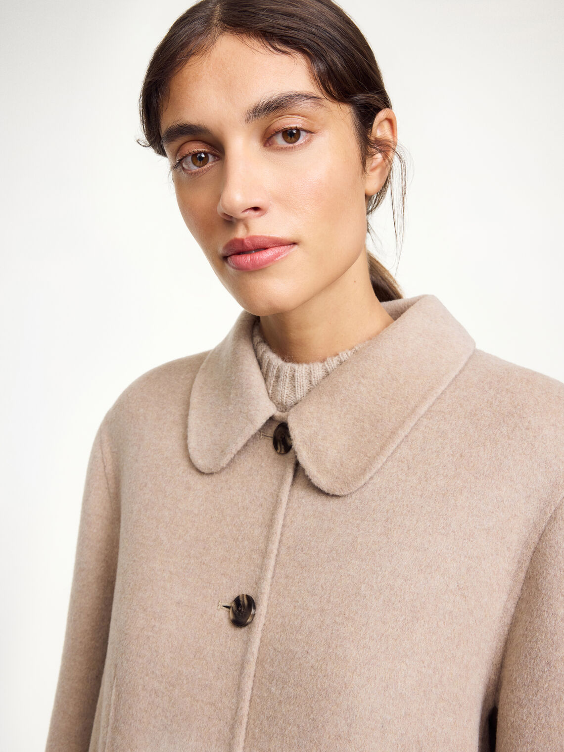 By Malene Birger Maelle kåpe i beige, med en rett passform, buet krage og laget av 100% ull.