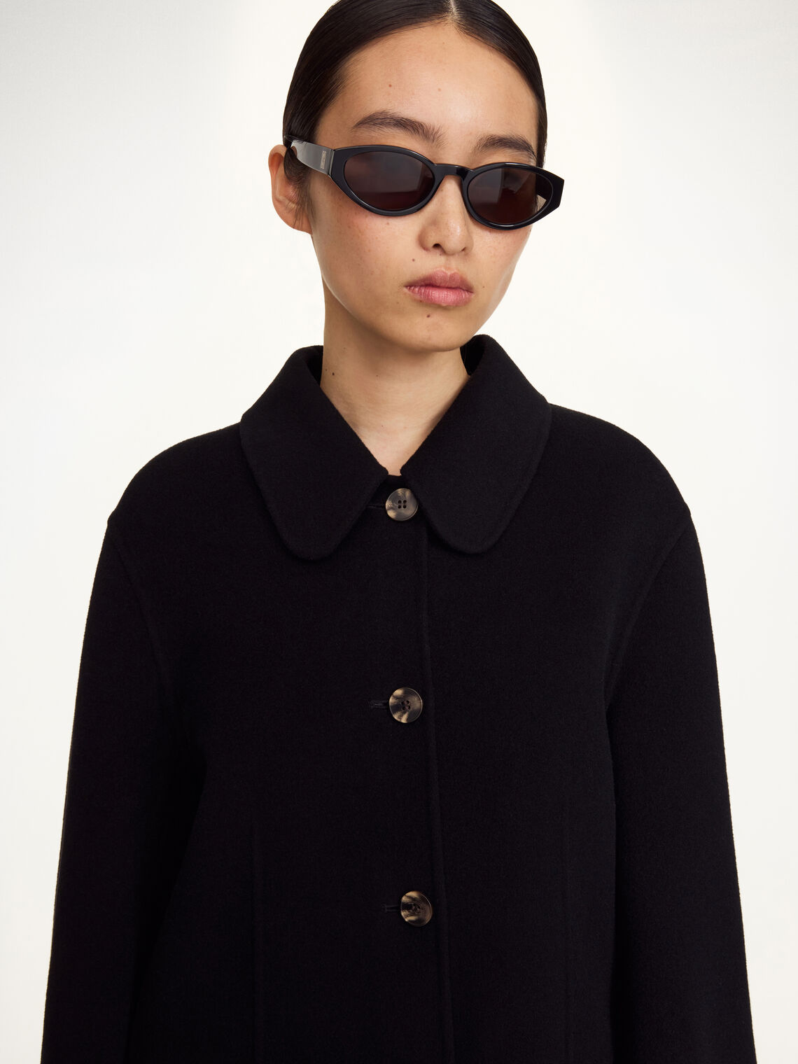 By Malene Birger Maelle kåpe i sort, med en rett passform, buet krage og laget av 100% ull.