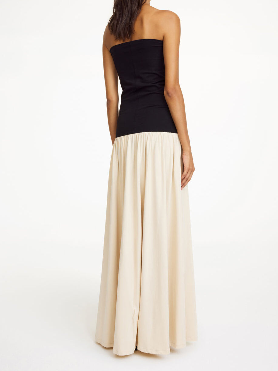 By Malene Birger Marciella kjole i sort og kremfarget, med en nedbrettbar tubetopp og voluminøst skjørt, laget av organisk bomull og elastan.