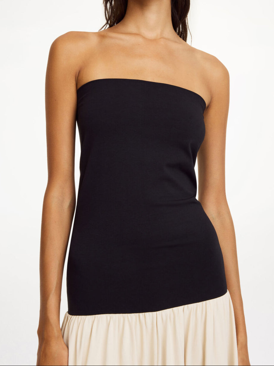 By Malene Birger Marciella kjole i sort og kremfarget, med en nedbrettbar tubetopp og voluminøst skjørt, laget av organisk bomull og elastan.