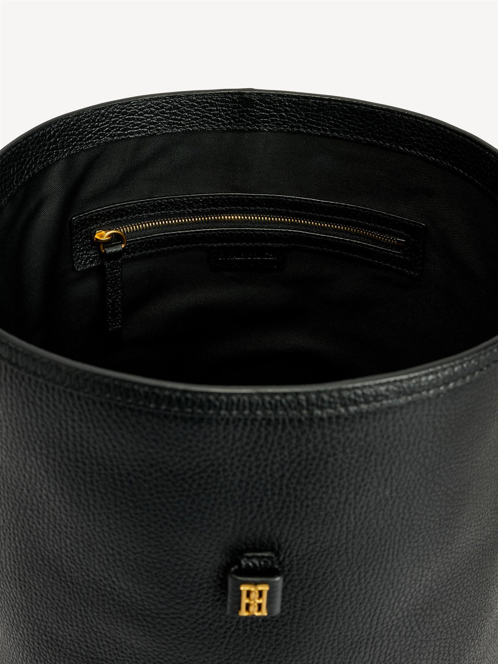 By Malene Birger Maryllon veske i sort skinn, med bøtteform og gullfarget monogram-emblem i front.