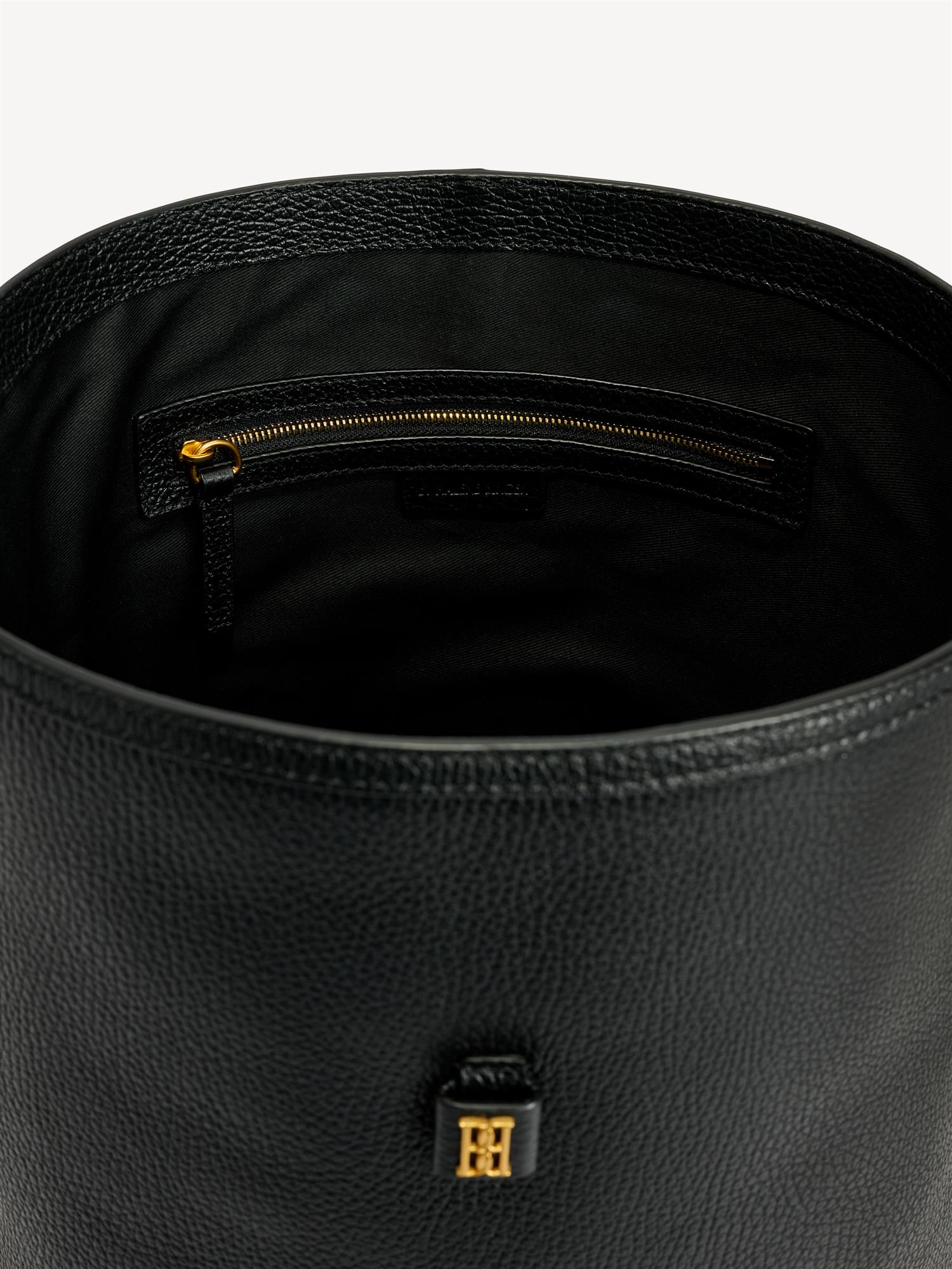 By Malene Birger Maryllon veske i sort skinn, med bøtteform og gullfarget monogram-emblem i front.