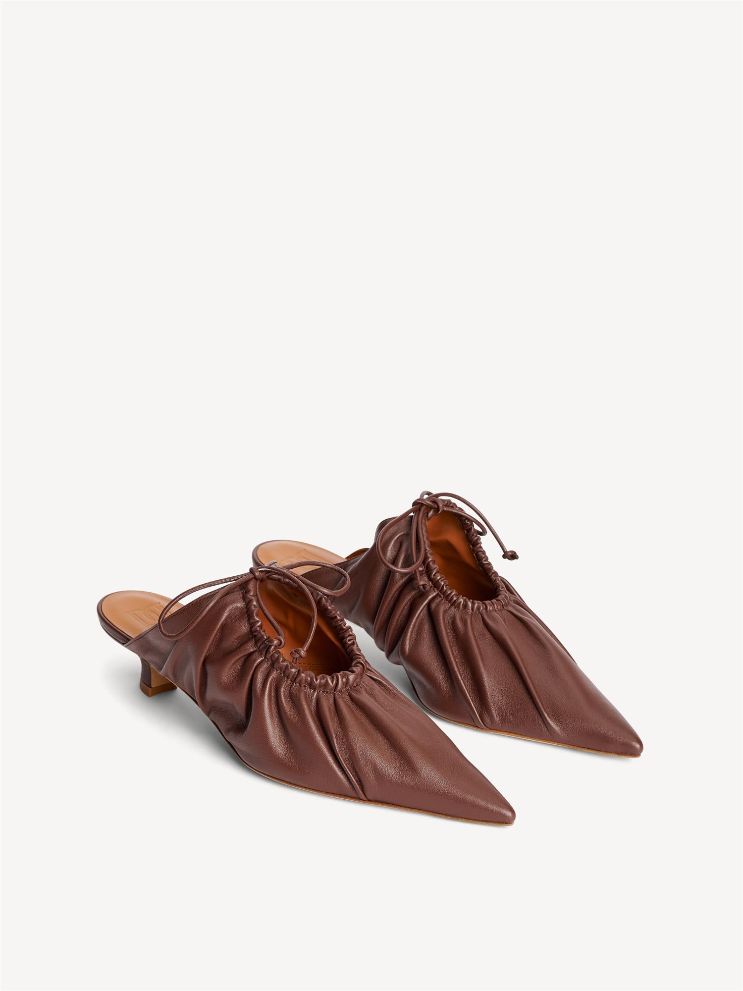 By Malene Birger Masey skinnmules i mørkebrun, laget av geiteskinn, med kitten-heels og en spiss silhuett.