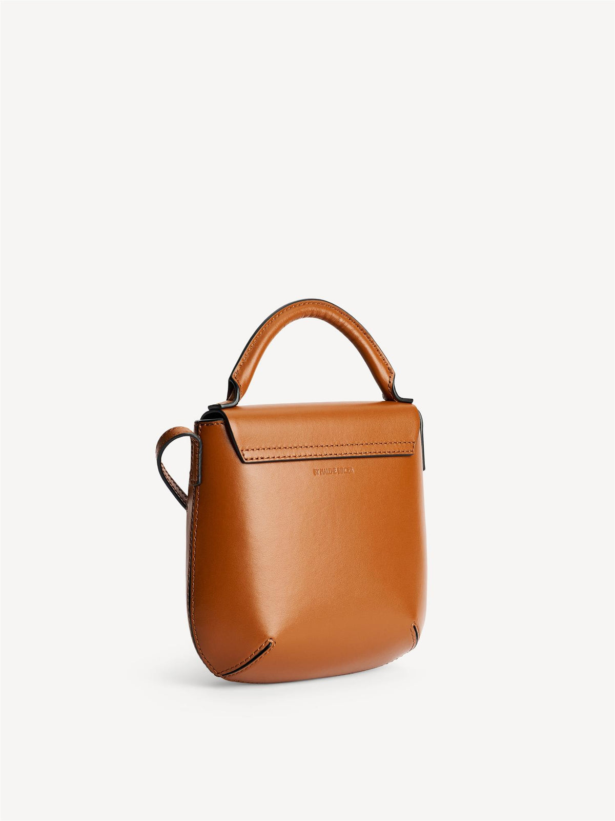 MEELA veske fra By Malene Birger i fargen brun, laget i 100% blank kuskinn. Liten, buet form med klaff og magnetlukking, justerbar stropp, bærehank og liten monogramdetalj i front.