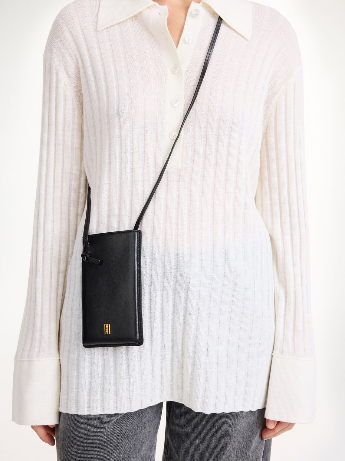 By Malene Birger mobilveske i sort, resirkulert skinn, med monogram-motiv og knutedetalj.