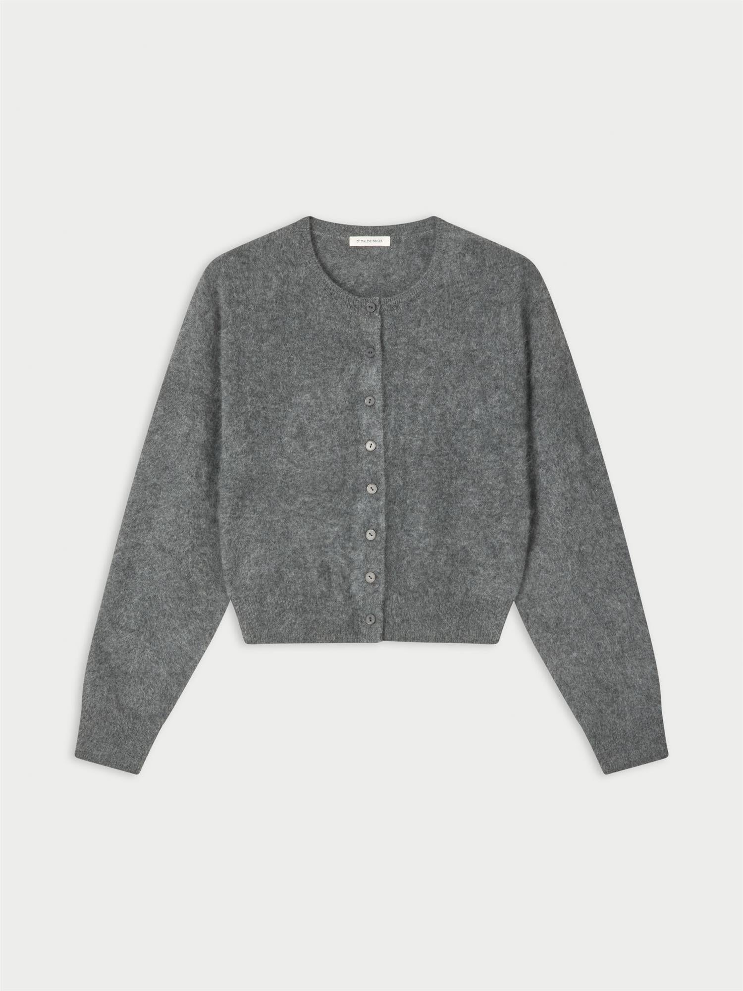 MONTANA cardigan fra By Malene Birger i fargen mørkegrå, laget i 100% cashmere. Rund hals, ribbestrikkede avslutninger og lukkes med knapper i front.