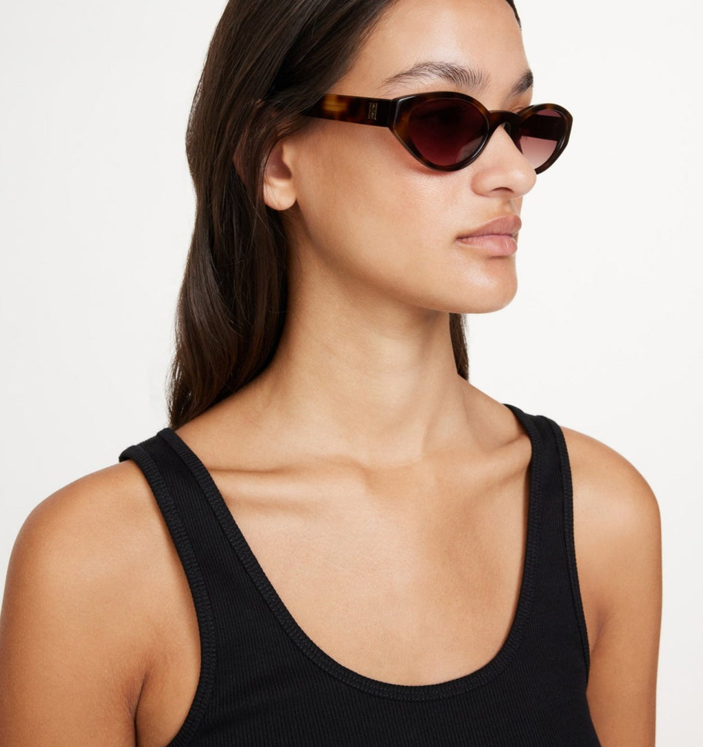 MYLA solbriller fra By Malene Birger i brun acetat med oval cat-eye ramme, mørke UV-beskyttende linser og monogram-emblem på siden.