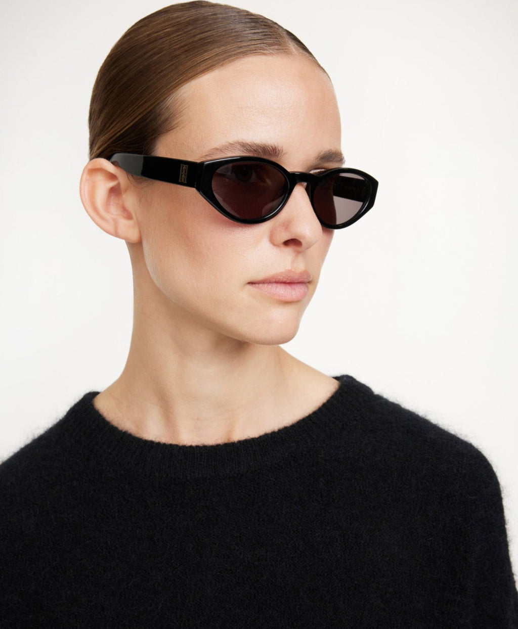 Sort oval cat-eye ramme i acetat, mørke UV-beskyttende linser, monogram-emblem på siden