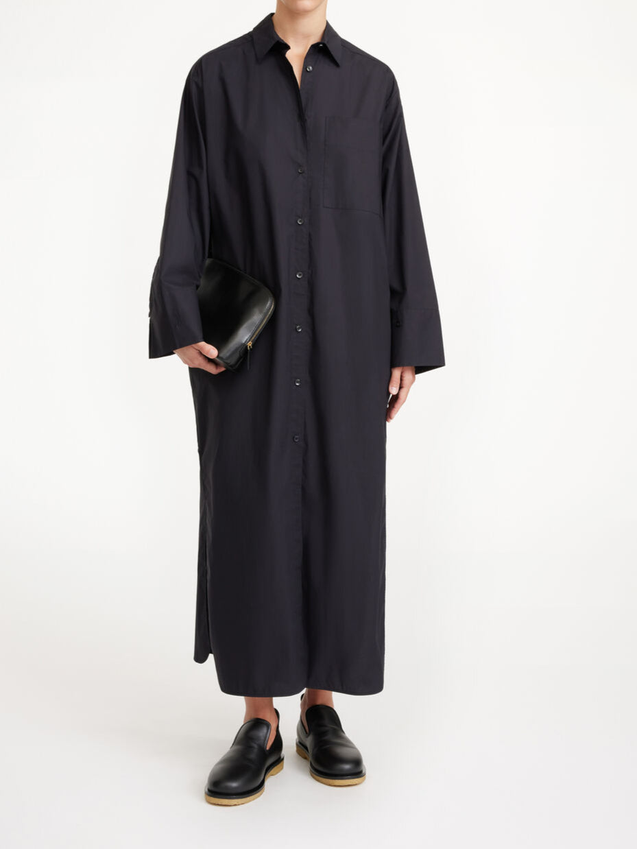 By Malene Birger Perros kjole i sort, laget av organisk bomull, med oversized passform, knapper i front og høy splitt på sidene.