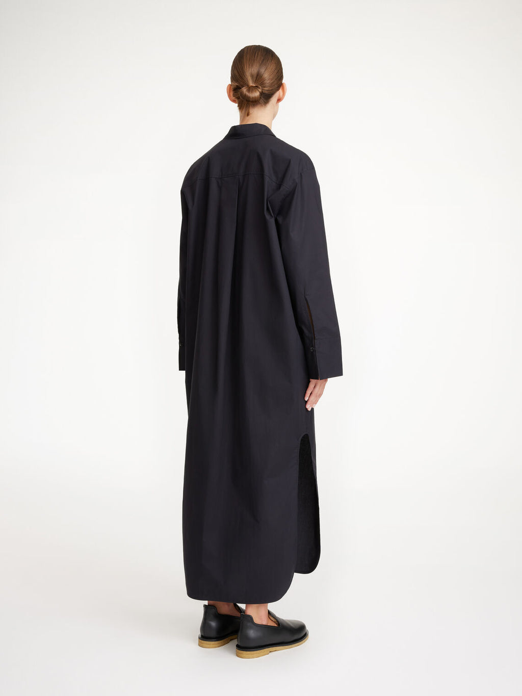 By Malene Birger Perros kjole i sort, laget av organisk bomull, med oversized passform, knapper i front og høy splitt på sidene.