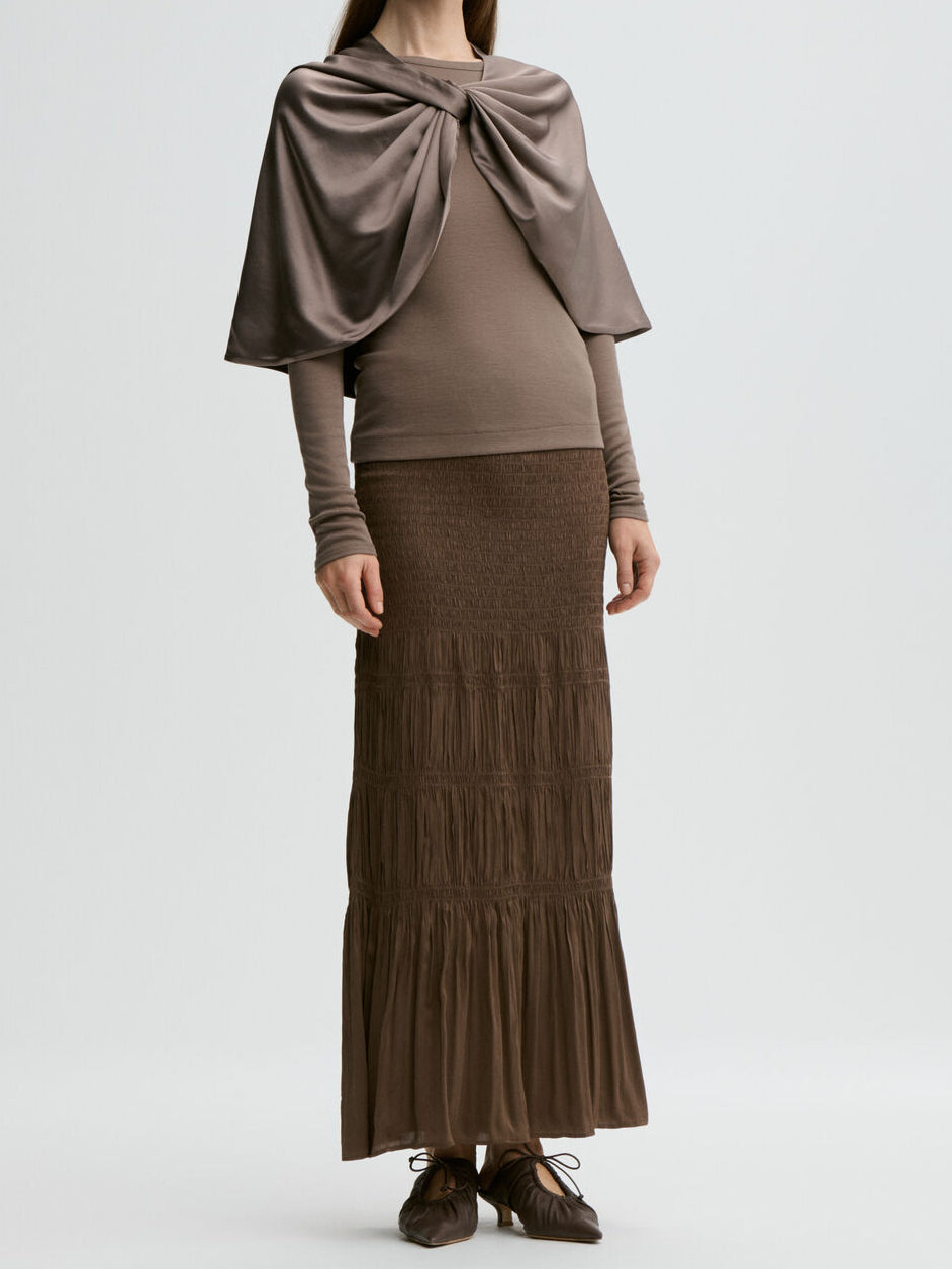 By Malene Birger PINLOS cape i brun materiale med Signatur Flower-print. Rund halsringning og lange fallende linjer.