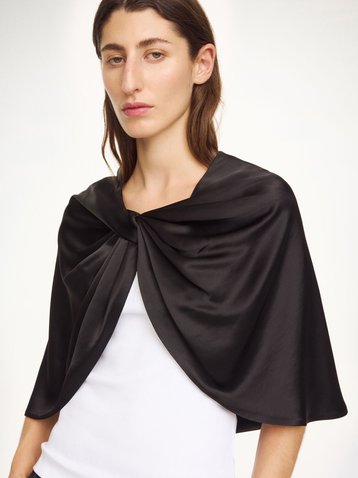 By Malene Birger PINLOS cape i sort materiale med Signatur Flower-print. Rund halsringning og lange fallende linjer.