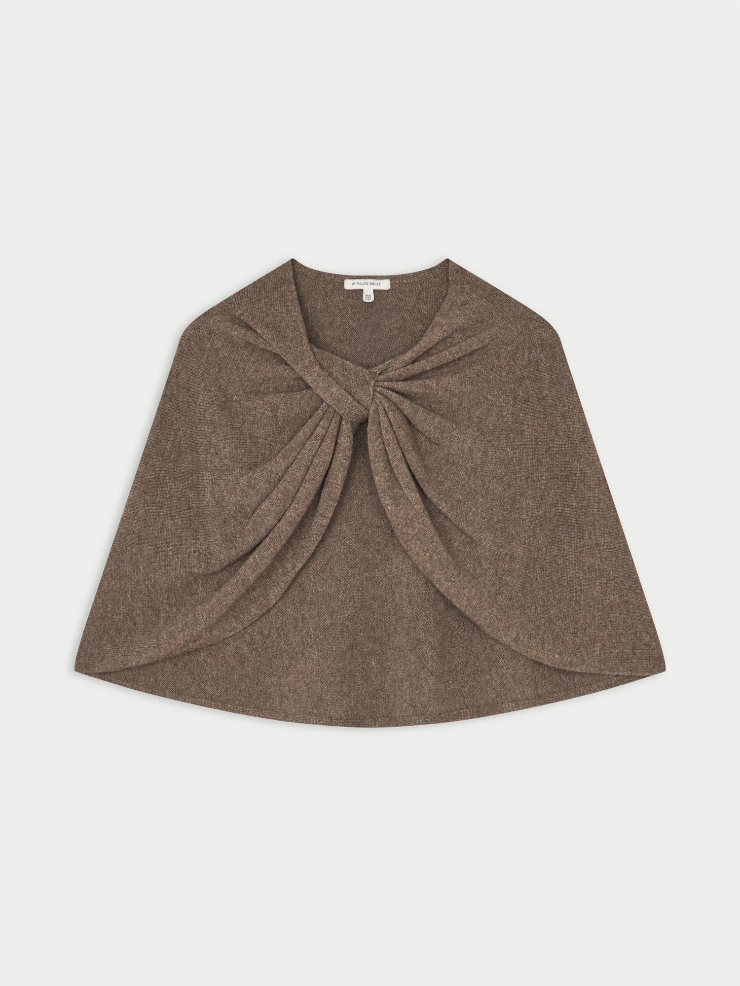PINNE cape fra By Malene Birger i fargen brun, laget i 75% merinoull og 25% yak. Knytedetalj i front som kan brukes foran, på siden eller bak.