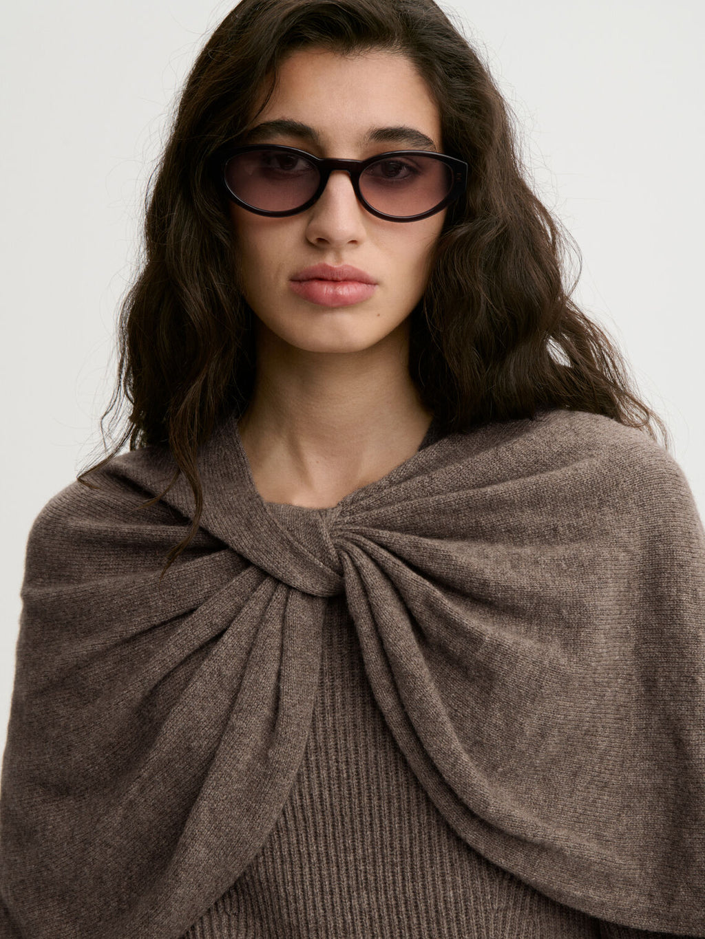 PINNE cape fra By Malene Birger i fargen brun, laget i 75% merinoull og 25% yak. Knytedetalj i front som kan brukes foran, på siden eller bak.
