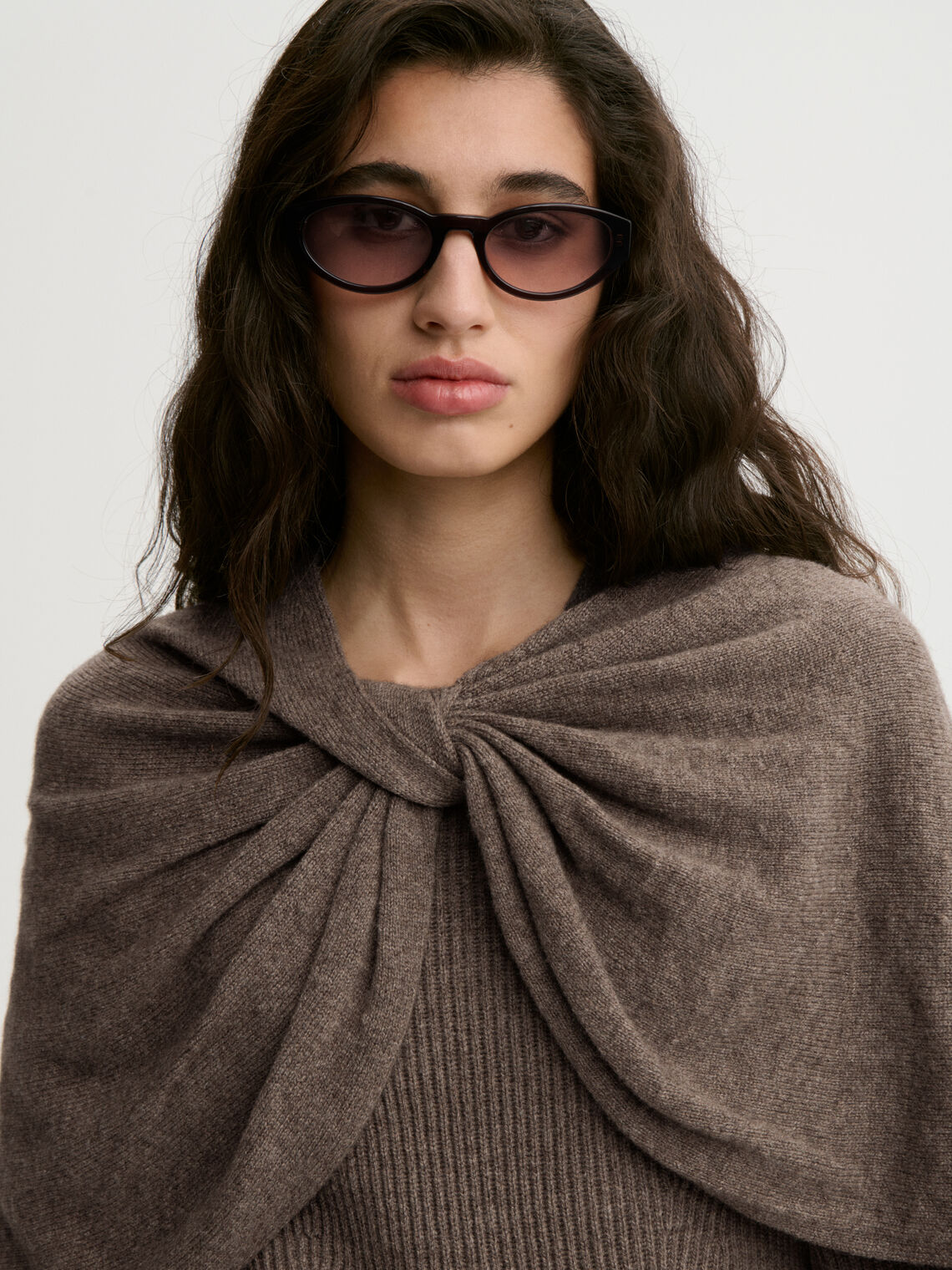 PINNE cape fra By Malene Birger i fargen brun, laget i 75% merinoull og 25% yak. Knytedetalj i front som kan brukes foran, på siden eller bak.
