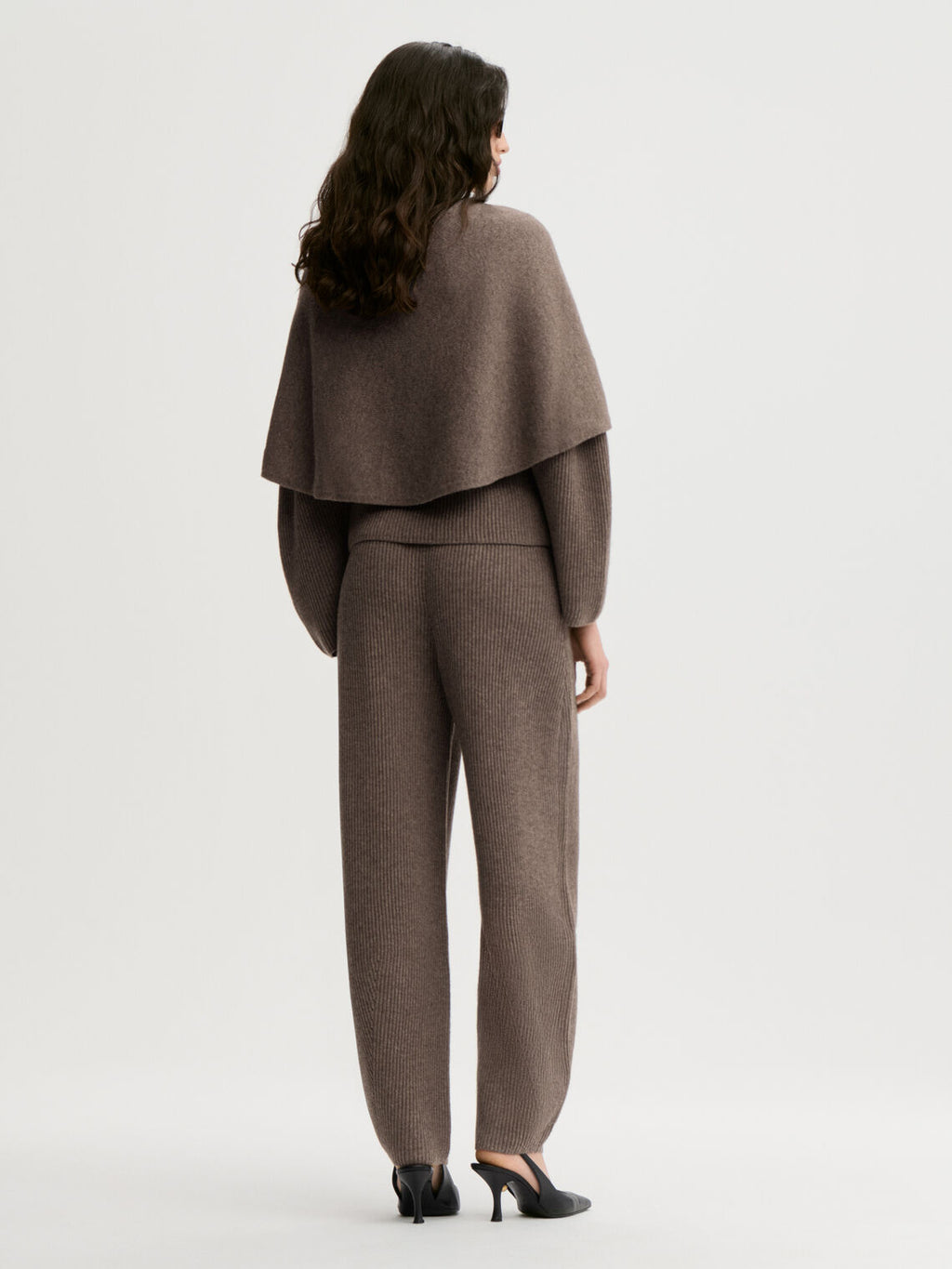 PINNE cape fra By Malene Birger i fargen brun, laget i 75% merinoull og 25% yak. Knytedetalj i front som kan brukes foran, på siden eller bak.
