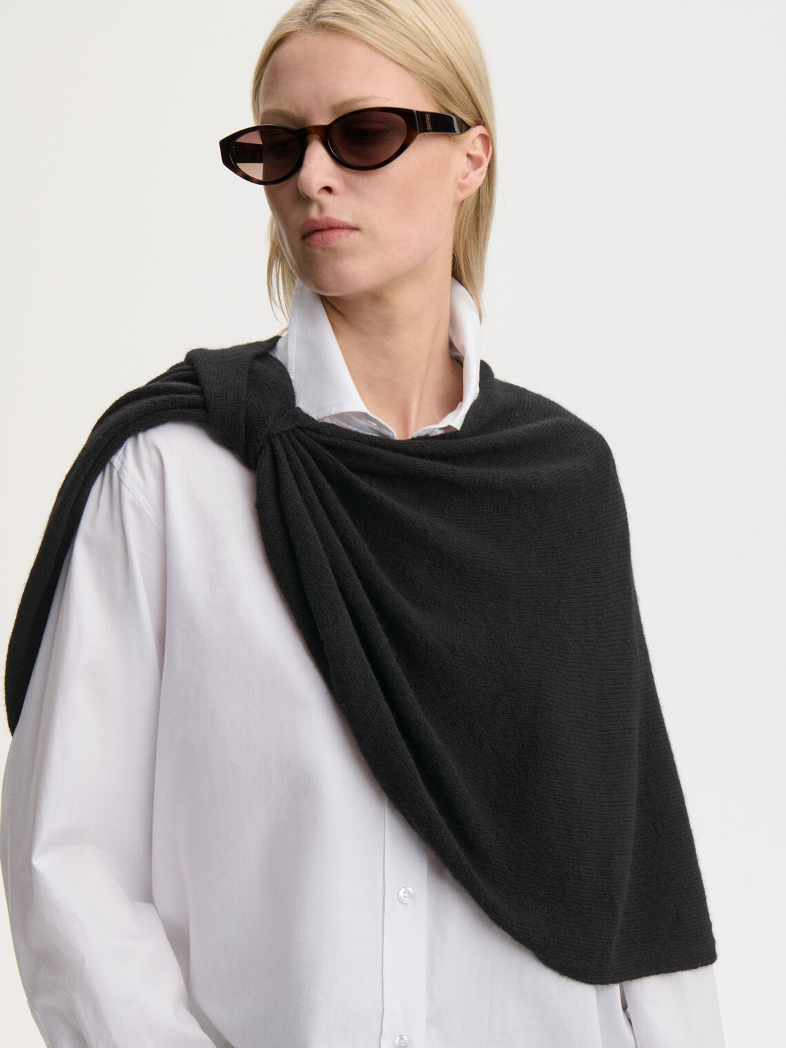 PINNE cape fra By Malene Birger i fargen sort, laget i 75% merinoull og 25% yak. Knytedetalj i front som kan brukes foran, på siden eller bak.