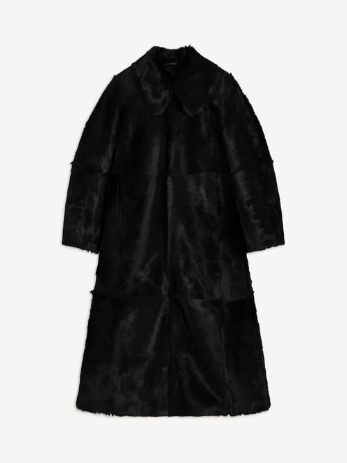 RAFAIA kåpe fra By Malene Birger i fargen sort, laget i 100% ekte, farget kalveskinn med langhåret pels. Lang lengde, glidelås som går begge veier og lommer i siden.