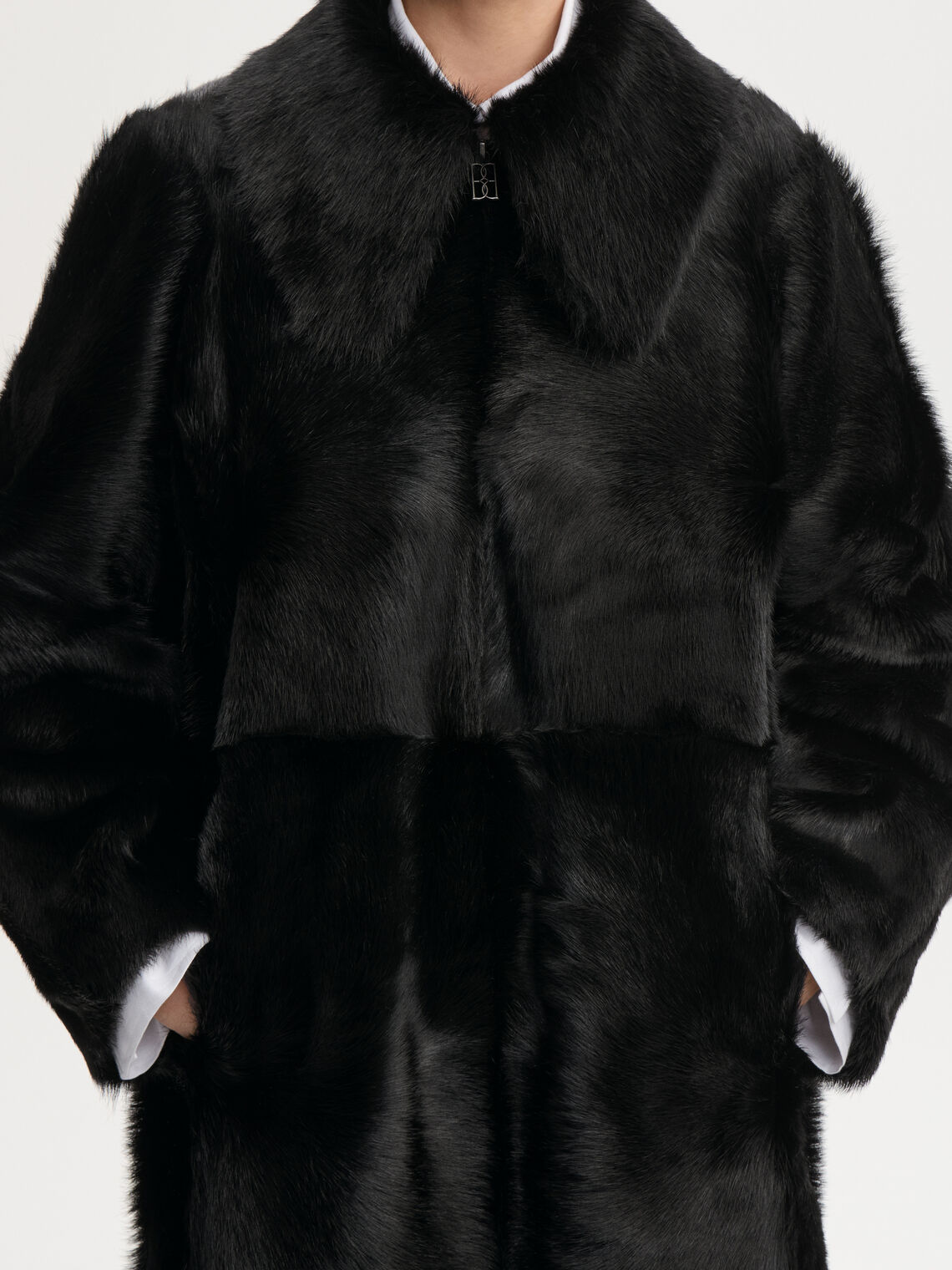 RAFAIA kåpe fra By Malene Birger i fargen sort, laget i 100% ekte, farget kalveskinn med langhåret pels. Lang lengde, glidelås som går begge veier og lommer i siden.