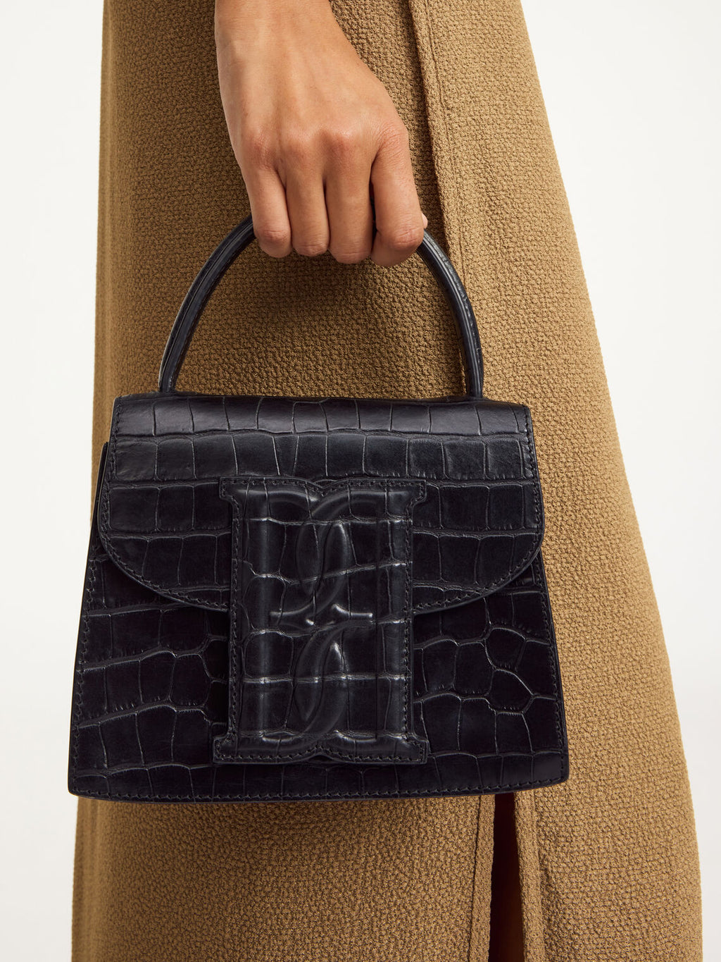 By Malene Birger Ramil veske i sort kalveskinn med krokomønster, monogram-motiv i front og justerbar skulderreim.