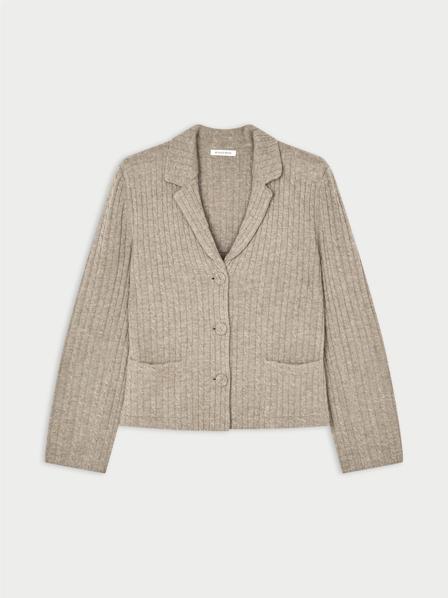 RIVA cardigan fra By Malene Birger i fargen beige, laget i 90% ull og 10% cashmere. Kabelstrikket struktur med v-hals, lommer i front, halvveis foret og cropped lengde.