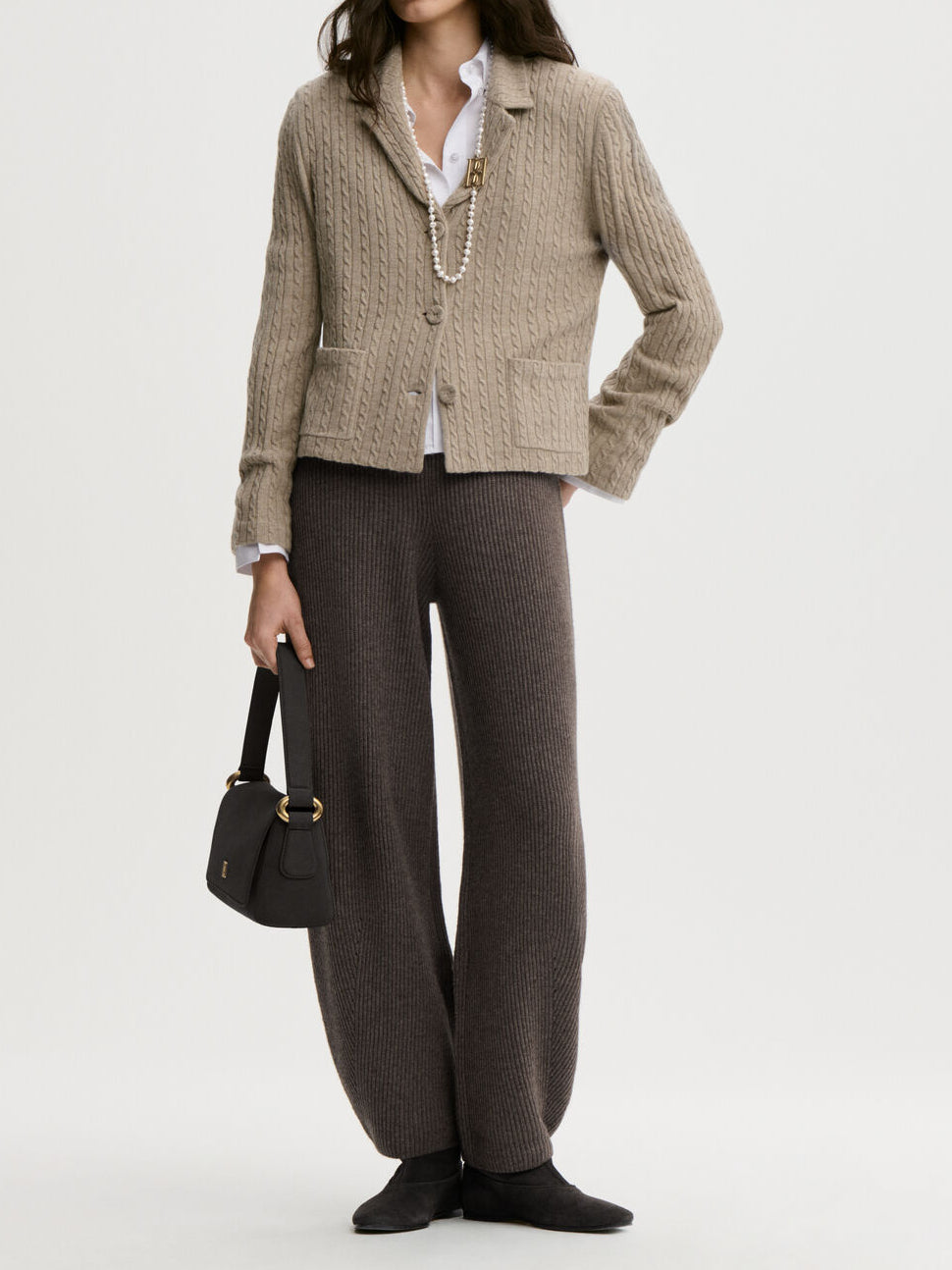 RIVA cardigan fra By Malene Birger i fargen beige, laget i 90% ull og 10% cashmere. Kabelstrikket struktur med v-hals, lommer i front, halvveis foret og cropped lengde.