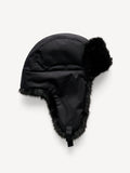 ROLLA vinterlue fra By Malene Birger i fargen sort, laget i vannavvisende 100% bomull med fuskepelskant. Klassisk flylue-silhuett med spenne under haken og brodert monogram.