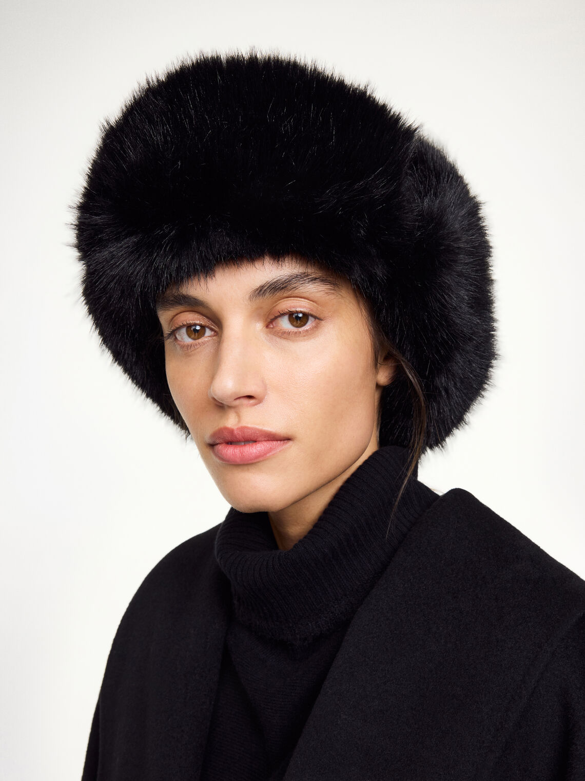 ROLLA vinterlue fra By Malene Birger i fargen sort, laget i vannavvisende 100% bomull med fuskepelskant. Klassisk flylue-silhuett med spenne under haken og brodert monogram.