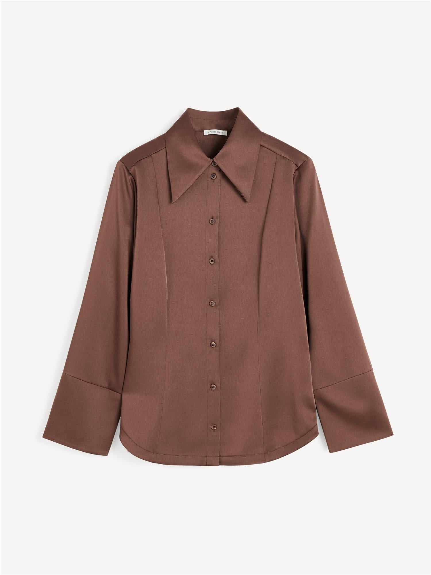 By Malene Birger Rosiannas skjortebluse i mørkebrun, med 70-talls krage, brede mansjetter og laget av en blanding av acetat og polyester.