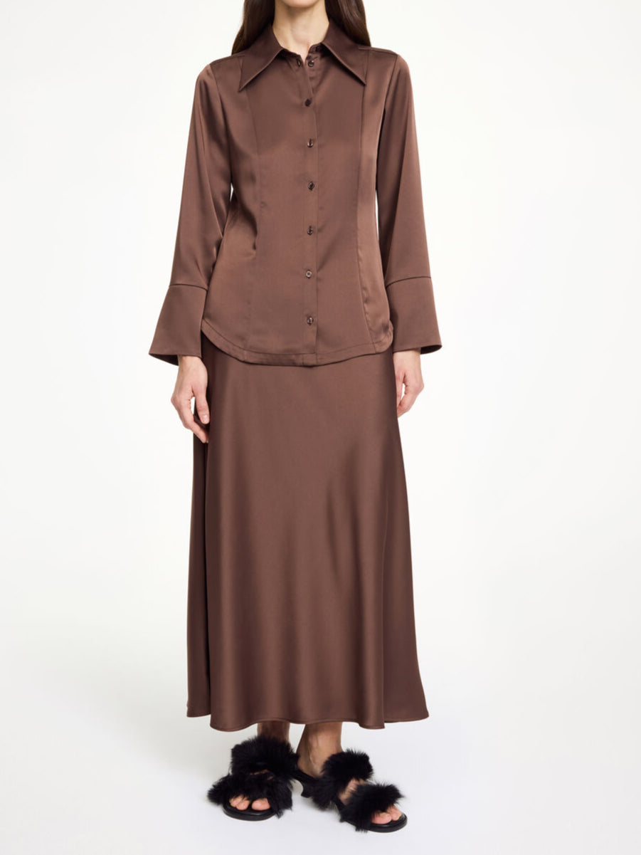 By Malene Birger Rosiannas skjortebluse i mørkebrun, med 70-talls krage, brede mansjetter og laget av en blanding av acetat og polyester.