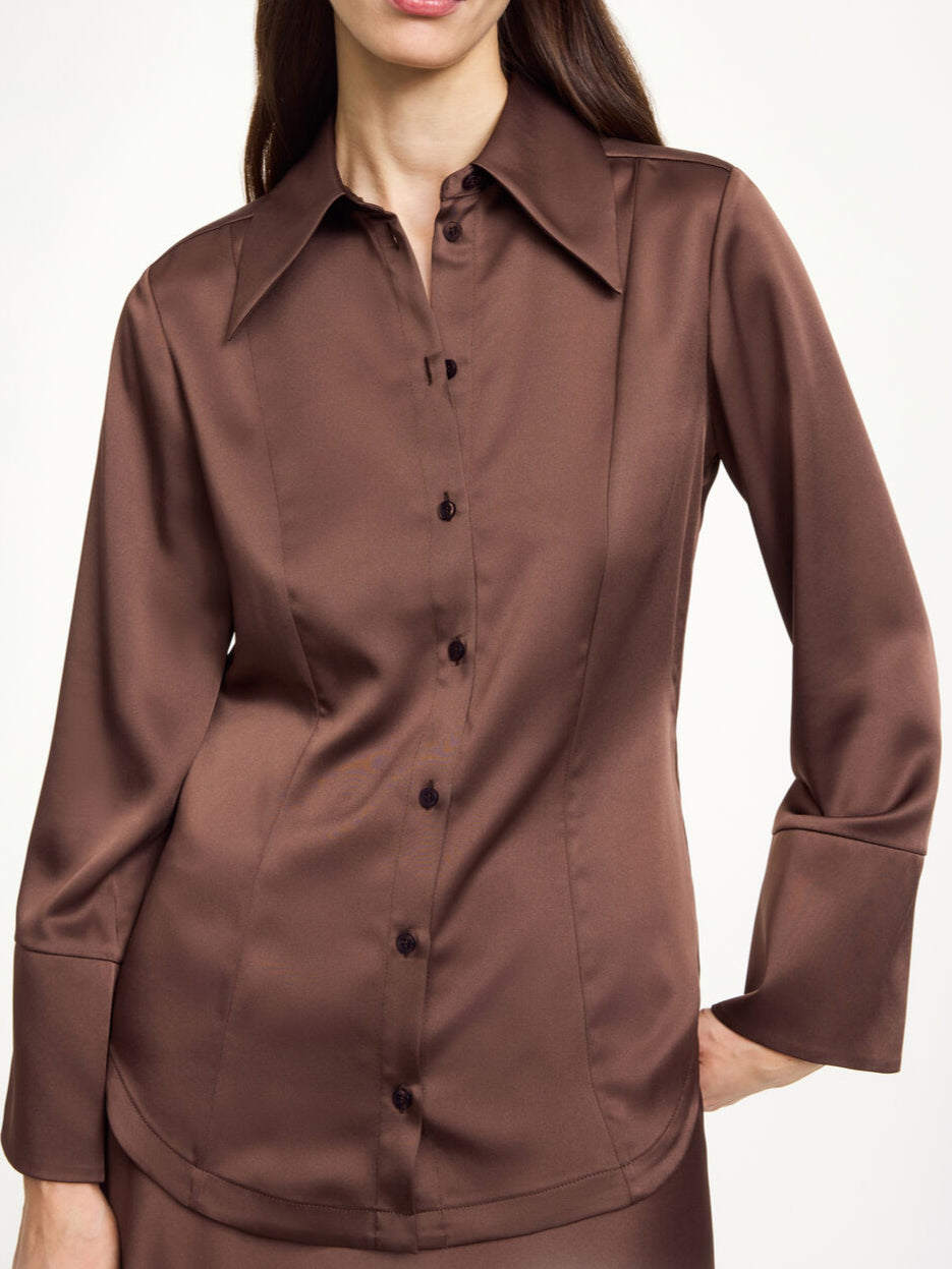 By Malene Birger Rosiannas skjortebluse i mørkebrun, med 70-talls krage, brede mansjetter og laget av en blanding av acetat og polyester.