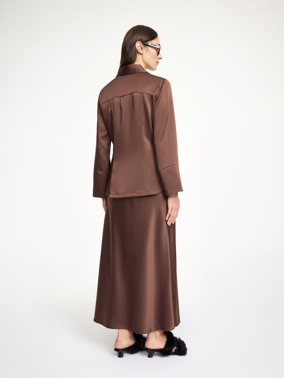 By Malene Birger Rosiannas skjortebluse i mørkebrun, med 70-talls krage, brede mansjetter og laget av en blanding av acetat og polyester.