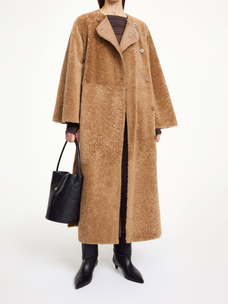 By Malene Birger Sandria lammeskinnskåpe i brun, laget av 100% lammeskinn og pels, med avtagbart belte og maksilengde.