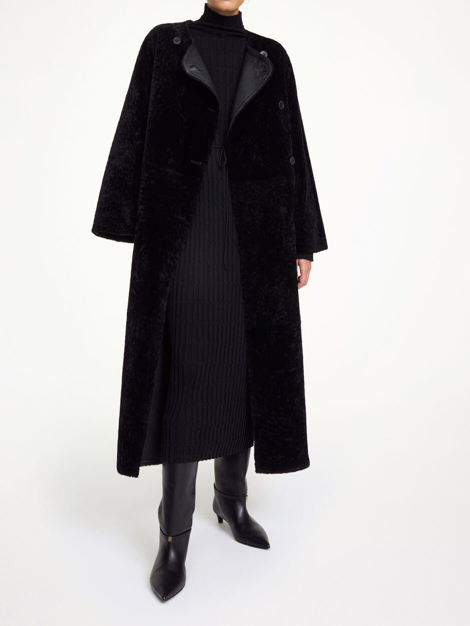 By Malene Birger Sandria lammeskinnskåpe i sort, laget av 100% lammeskinn og pels, med avtagbart belte og maksilengde.