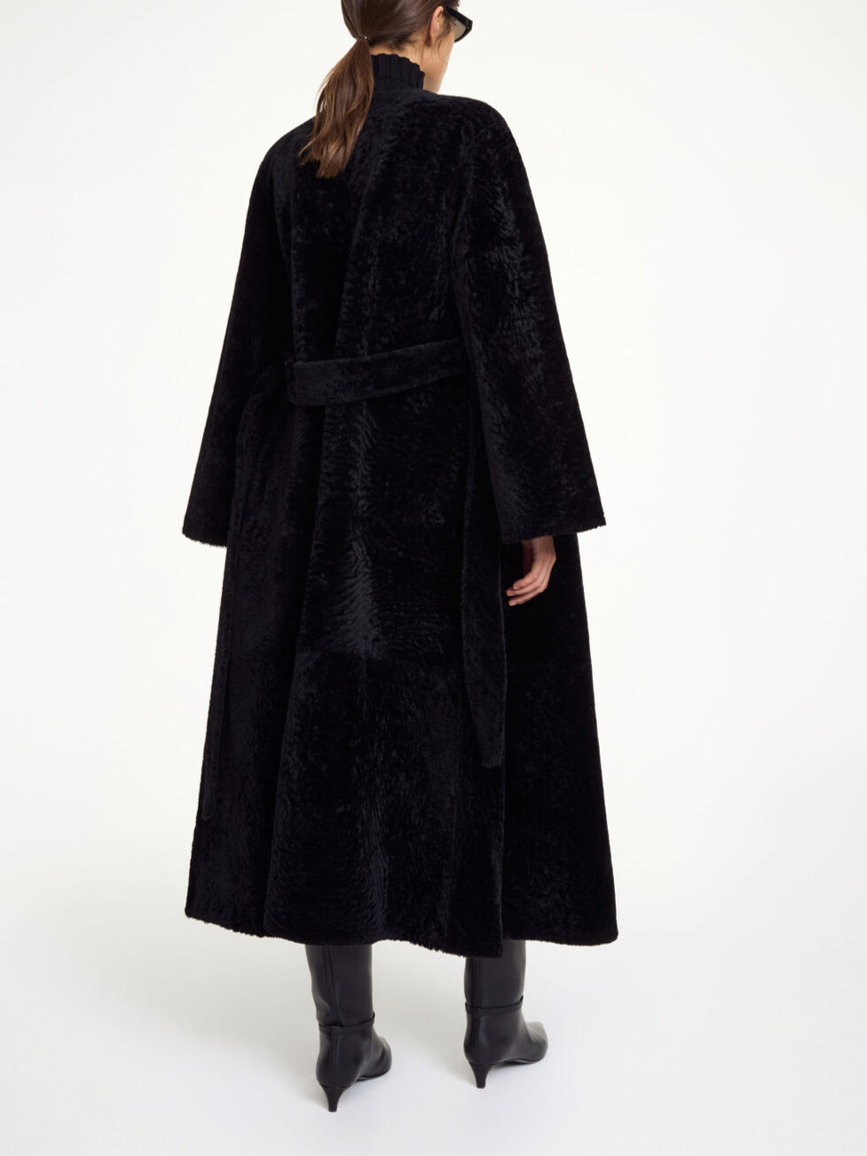 By Malene Birger Sandria lammeskinnskåpe i sort, laget av 100% lammeskinn og pels, med avtagbart belte og maksilengde.