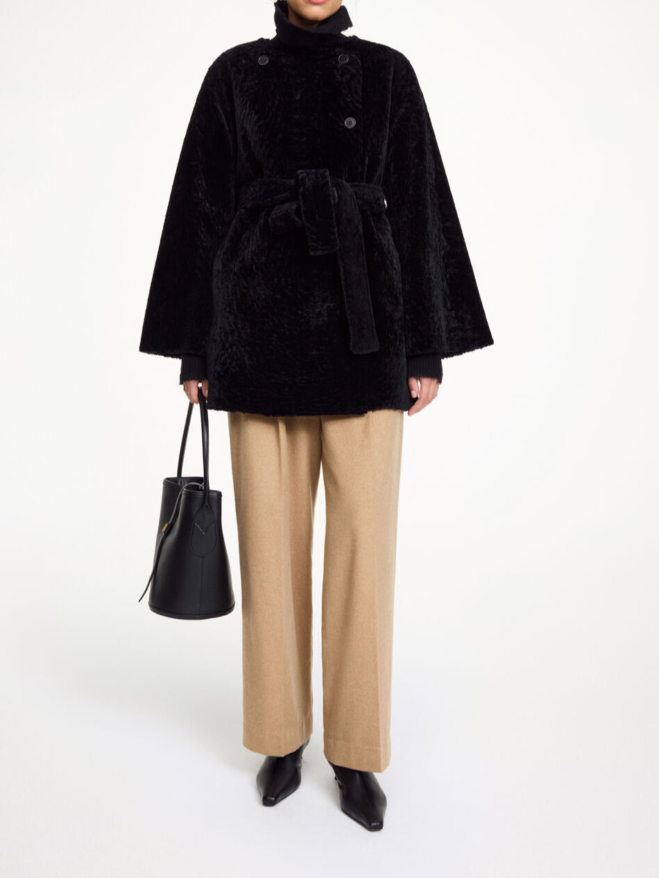 By Malene Birger Sannie kåpe i sort, laget av 100% lammeskinn og pels, med en tidløs og kort design.