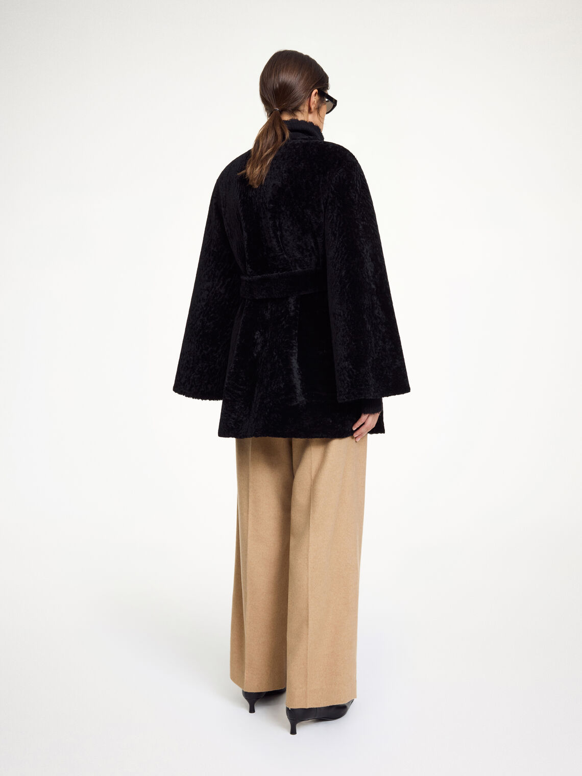 By Malene Birger Sannie kåpe i sort, laget av 100% lammeskinn og pels, med en tidløs og kort design.