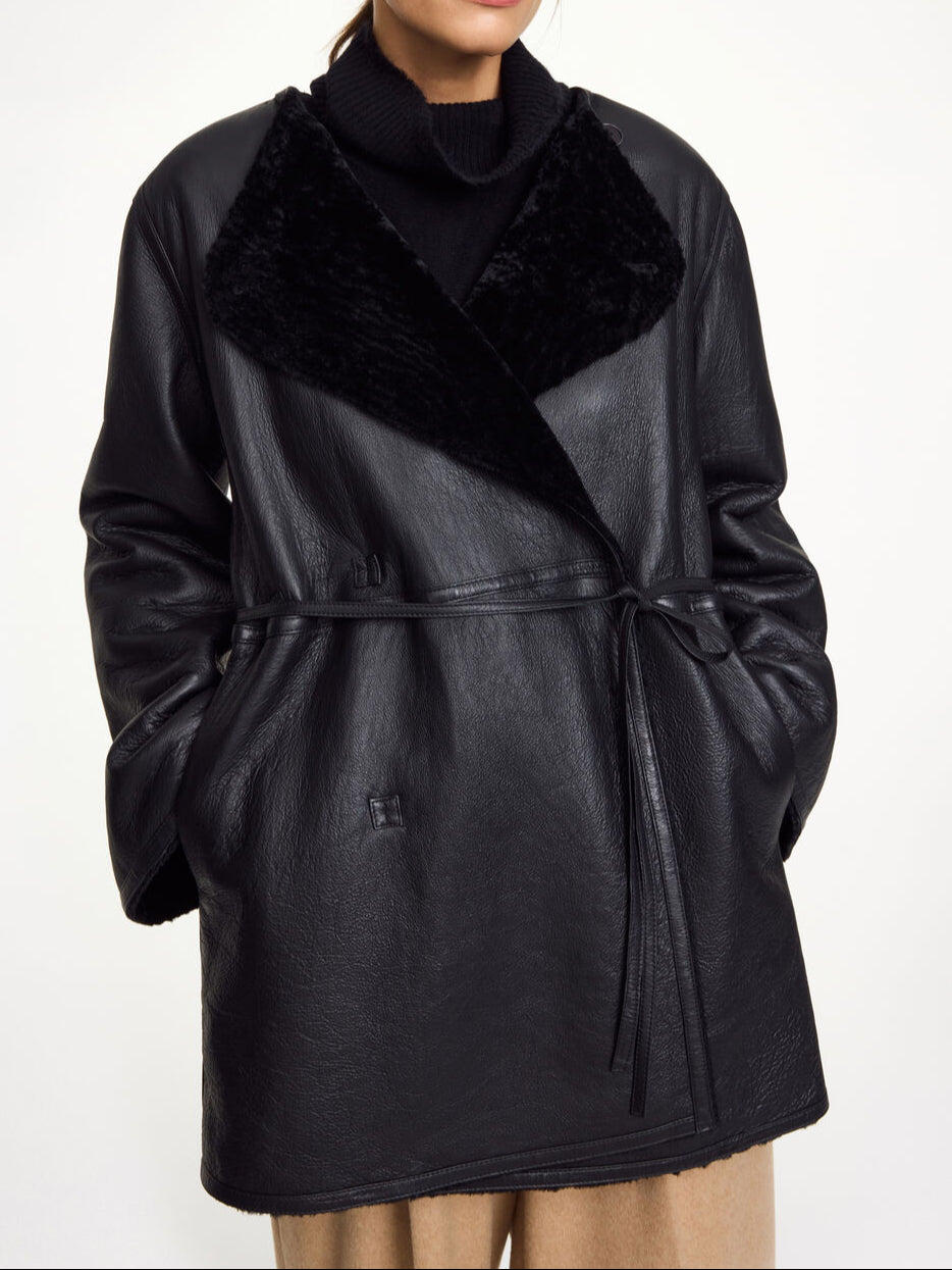 By Malene Birger Sannie kåpe i sort, laget av 100% lammeskinn og pels, med en tidløs og kort design.