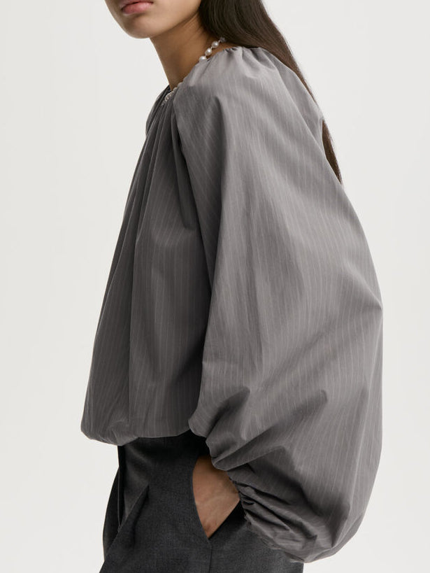SEMARA bluse fra By Malene Birger i fargen grå, laget i 100% organisk bomull. Raglanermer med ballongfasong, elastisk båthalsinspirert utringning, strikk i mansjettene og cropped lengde.