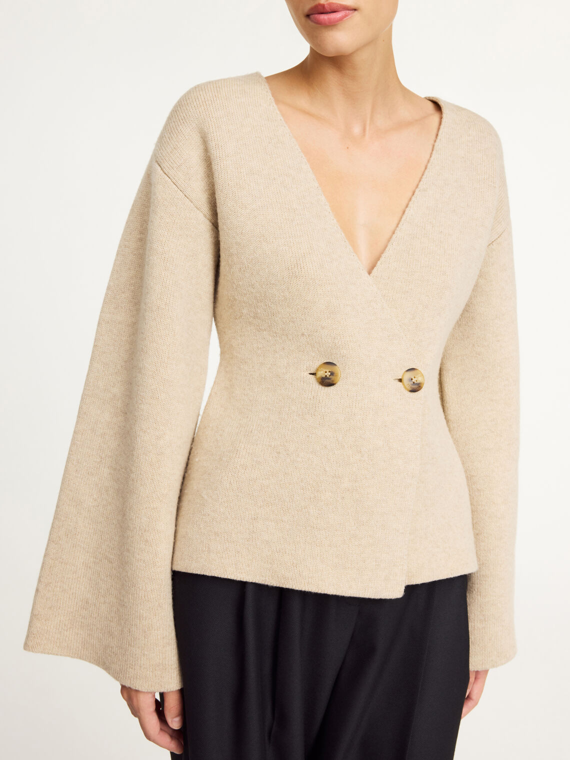 By Malene Birger Tinley cardigan i beige, med et dobbeltspent uttrykk og feminine trompetarmer, laget av ull og elastan.