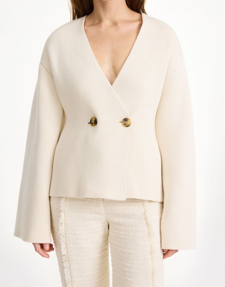 By Malene Birger Tinley cardigan i hvit, med et dobbeltspent uttrykk og feminine trompetarmer, laget av ull, bomull og elastan.