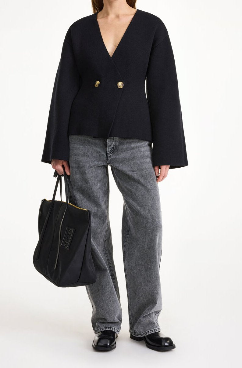By Malene Birger Tinley cardigan i sort, med et dobbeltspent uttrykk og feminine trompetarmer, laget av ull, bomull og elastan.